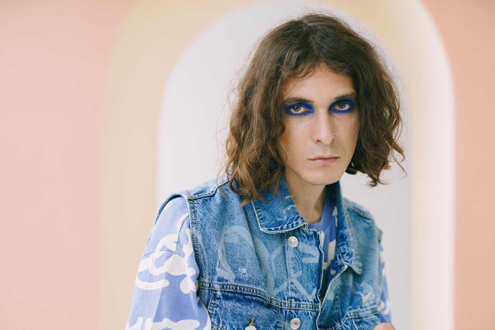 Porträt einer Person mit bemalter Jeansweste und kräftigem blauem Augen-Make-up